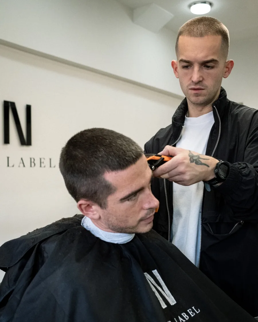 Barber cutting a client’s hair at No Label